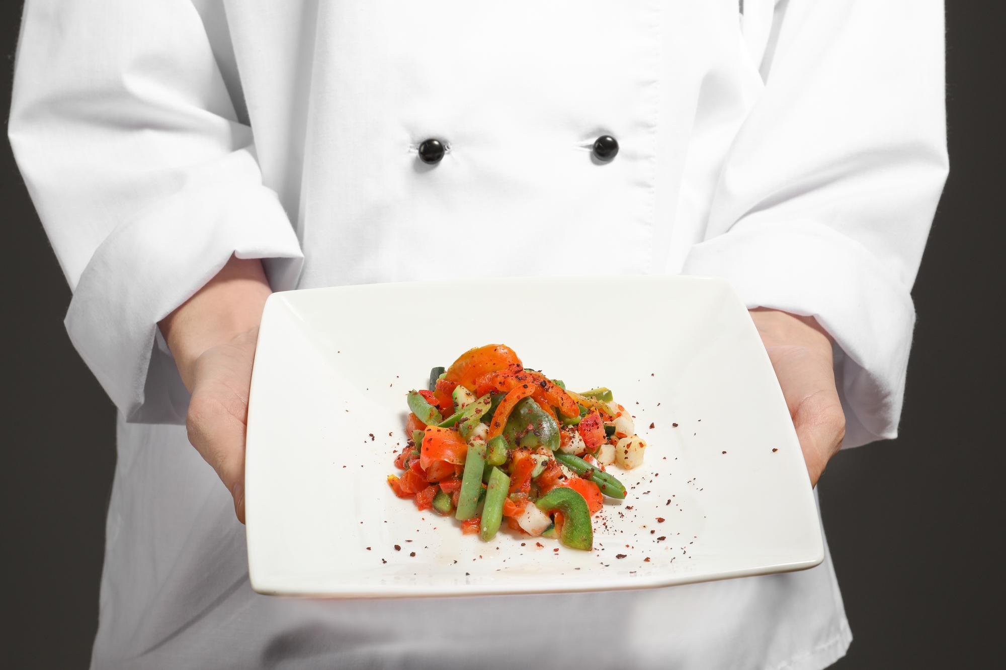 Hands preparing a modern plated dish in a sleek kitchen